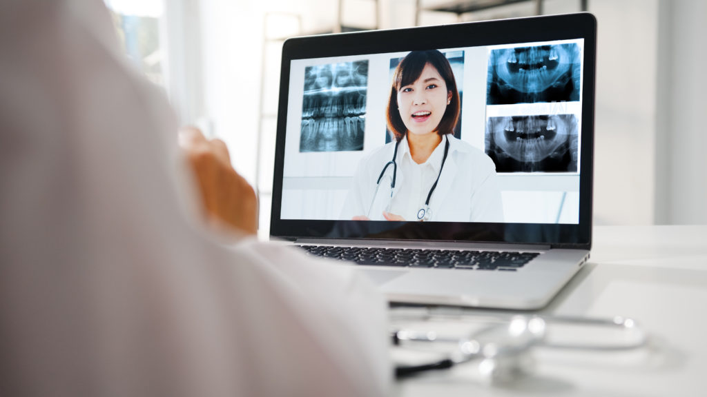 Woman speaking on laptop in front of dental x-rays. 6Connex case study or FMC's virtual event.