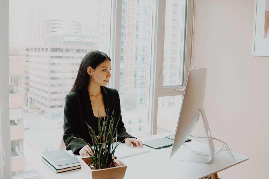 Chief Marketing Officer looking at desktop computer in their office with a window planning their Virtual Environment